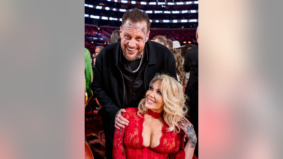 Jelly Roll posing alongside his wife Bunny Xo as they smile during the Grammy Awards.