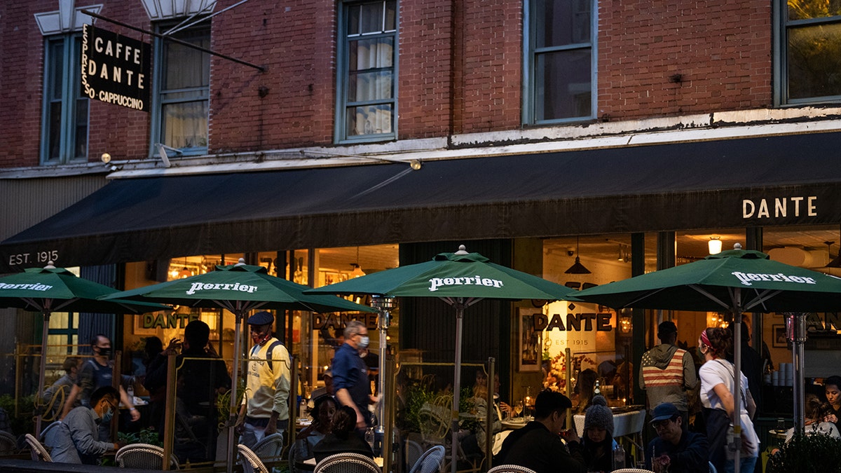 Cena all'aperto al Caffe Dante a New York City, con ombrelloni verdi Perrier e clienti seduti all'esterno.