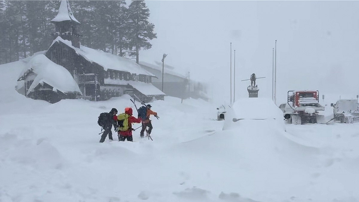 Thick layers of snow on a town with people walking and holding their skis