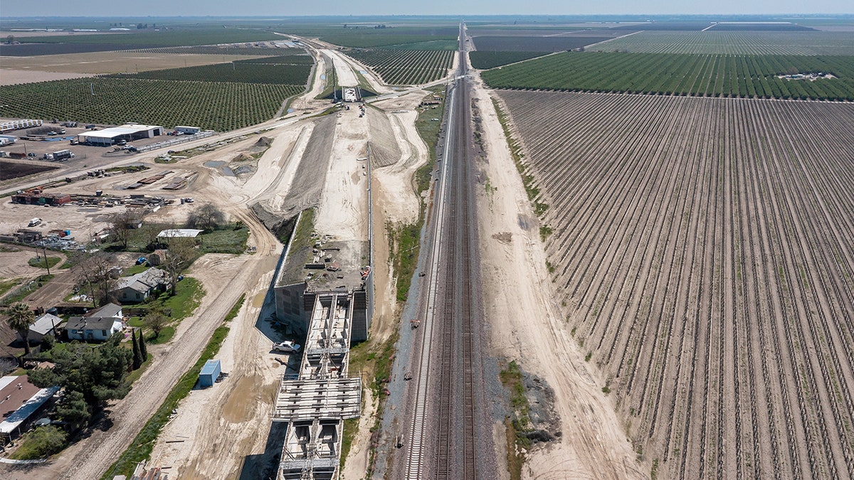 Equipes de construção e equipamentos pesados ​​trabalhando em uma estrutura ferroviária elevada em Fresno County, Califórnia