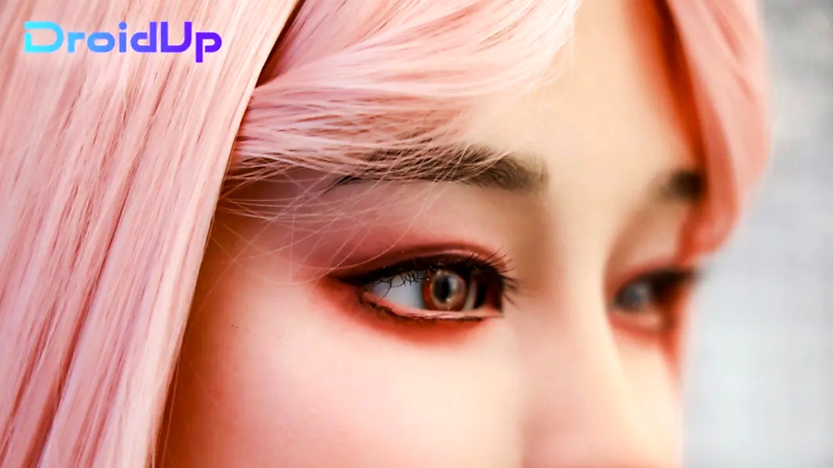 Close up of human-like robot with pink hair.