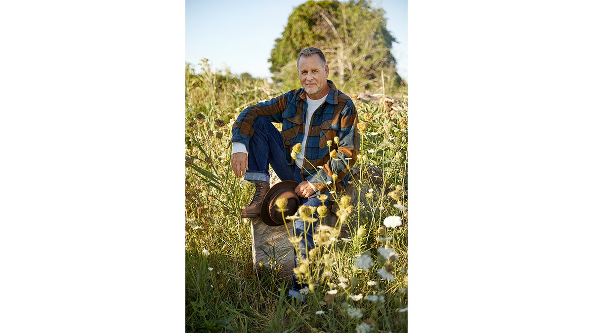Dave Coulier sits with his hand resting on his knee