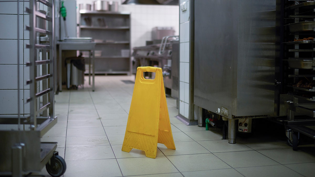 Caution sign noting wet floor in restaurant kitchen.