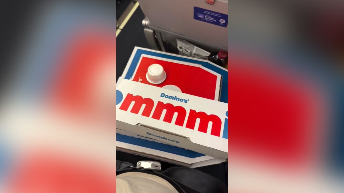 Mom and travel blogger Ali Van De Graaff holding pizza boxes in lap on place.