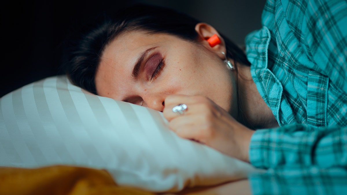 woman takes nap with orange foam ear plug in her ear
