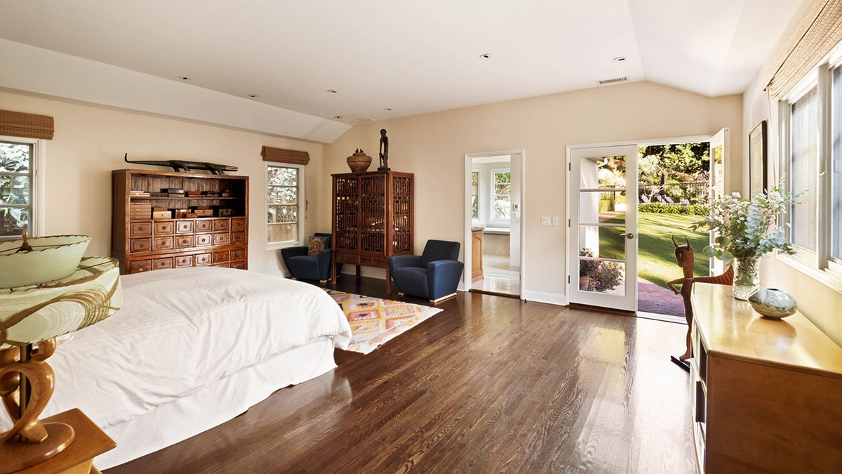 The spacious primary bedroom features access to the manicured lawn outside.