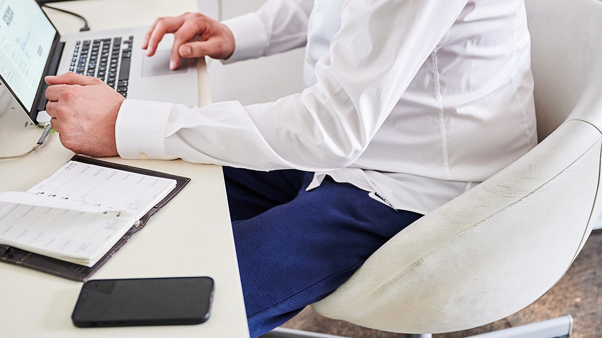 Persona seduta alla scrivania che digita sul computer.