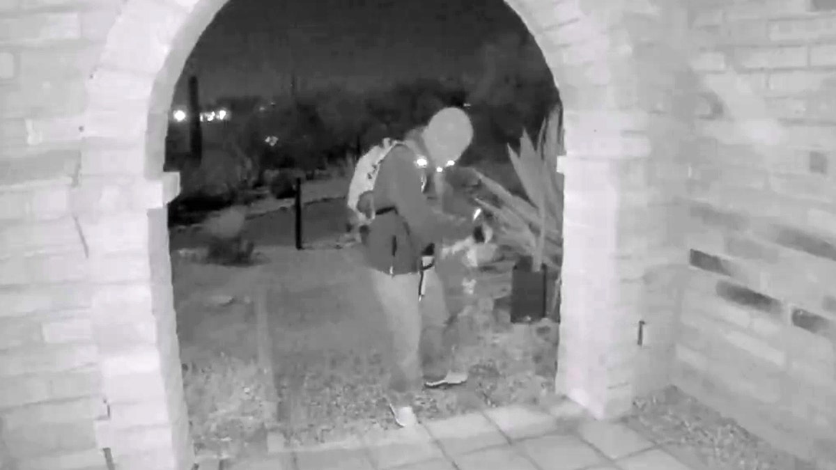 A view from a doorbell camera showing an armed individual outside the residence of Nancy Guthrie in Tucson, Arizona