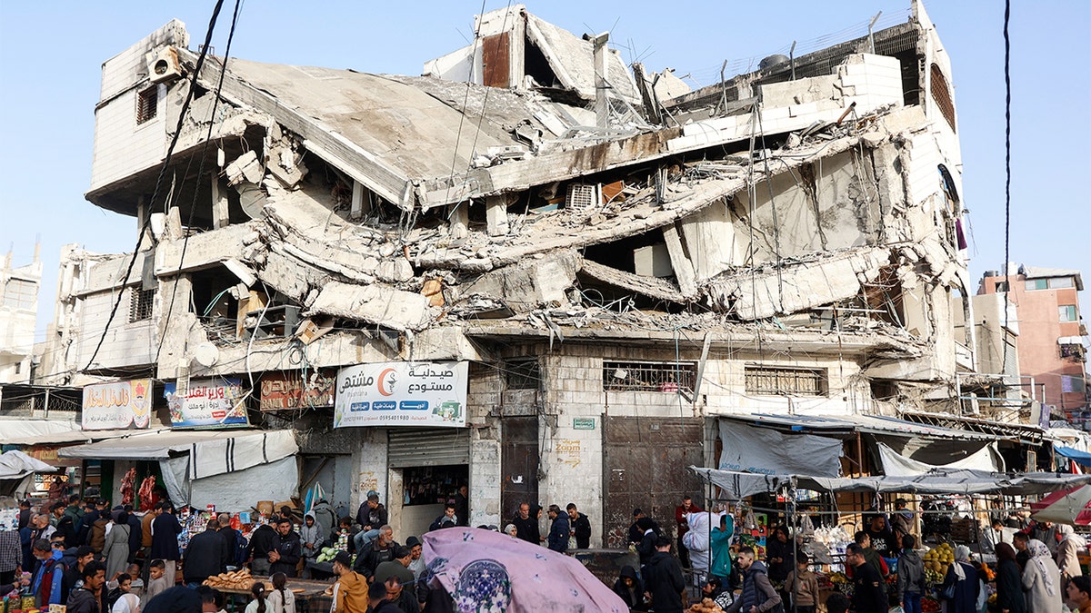 Los comerciantes compran alimentos en un mercado abierto entre los escombros de un edificio dañado en la ciudad de Gaza.