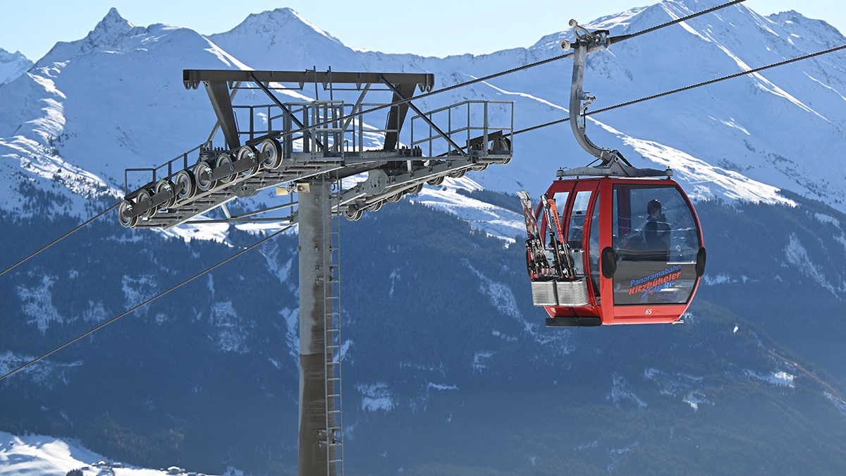 Red cable car gondola traveling over snowy alpine mountains at a ski resort in Austria.