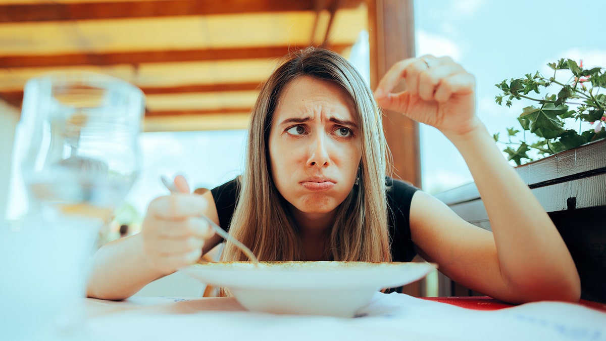Woman looking upset about finding hair in her food at restaurant