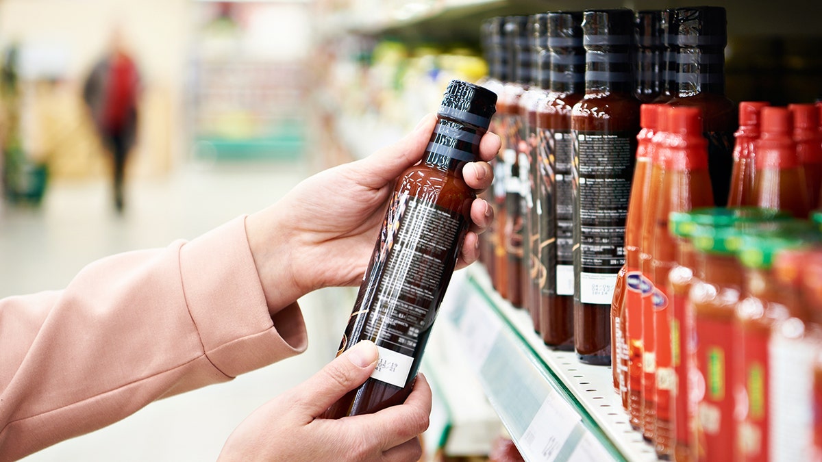 Shopper's hands seen holding hot cause bottle at grocery store.