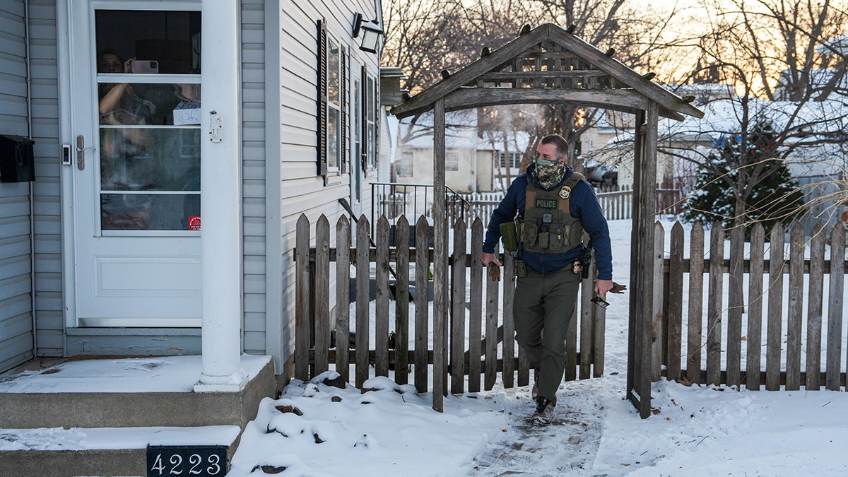 A federal agent walking through a gate at a house in Minneapolis.