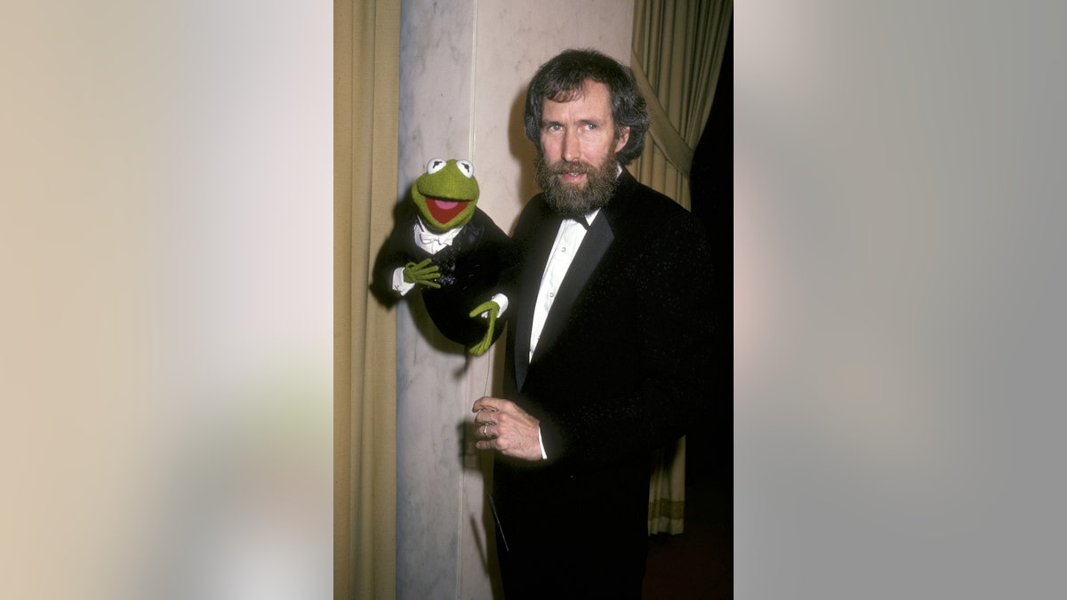 Jim Henson holding Kermit the Frog in a suit.