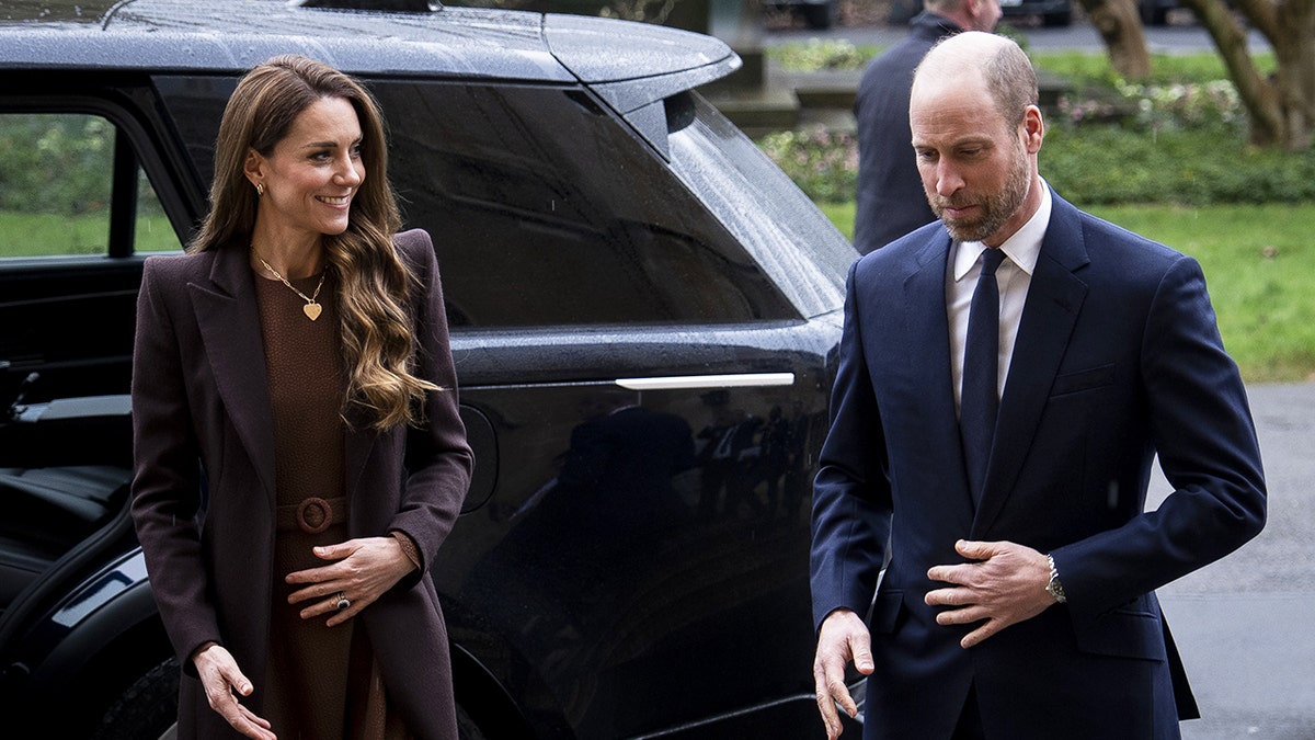 Príncipe William e Kate Middleton caminhando juntos na frente de um carro preto.