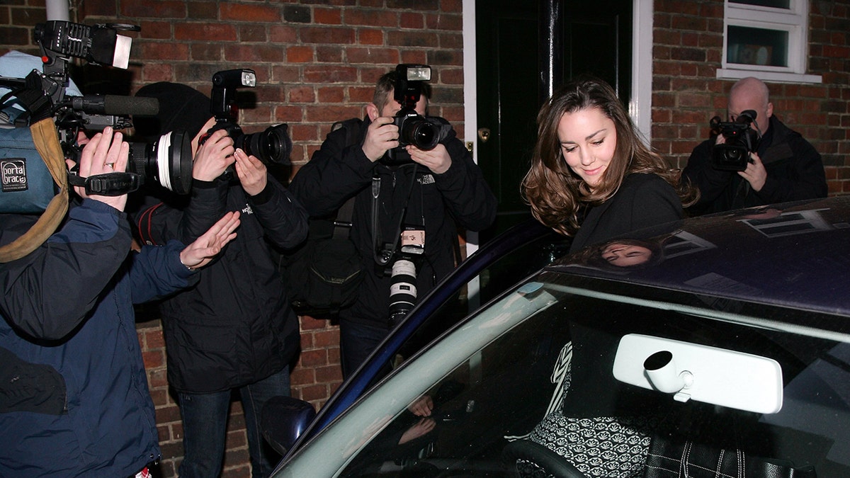 Kate Middleton being photographed by paparazzi as she enters her car.