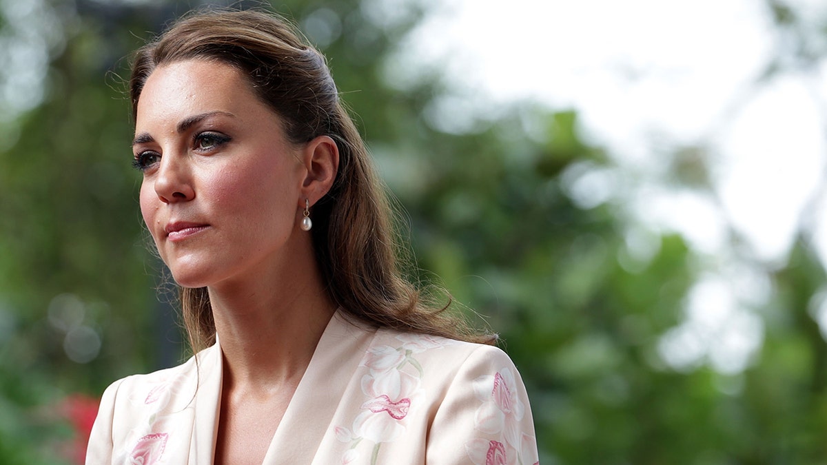 A close-up of Kate Middleton looking concerned in a powder pink suit while traveling in Southeast Asia.