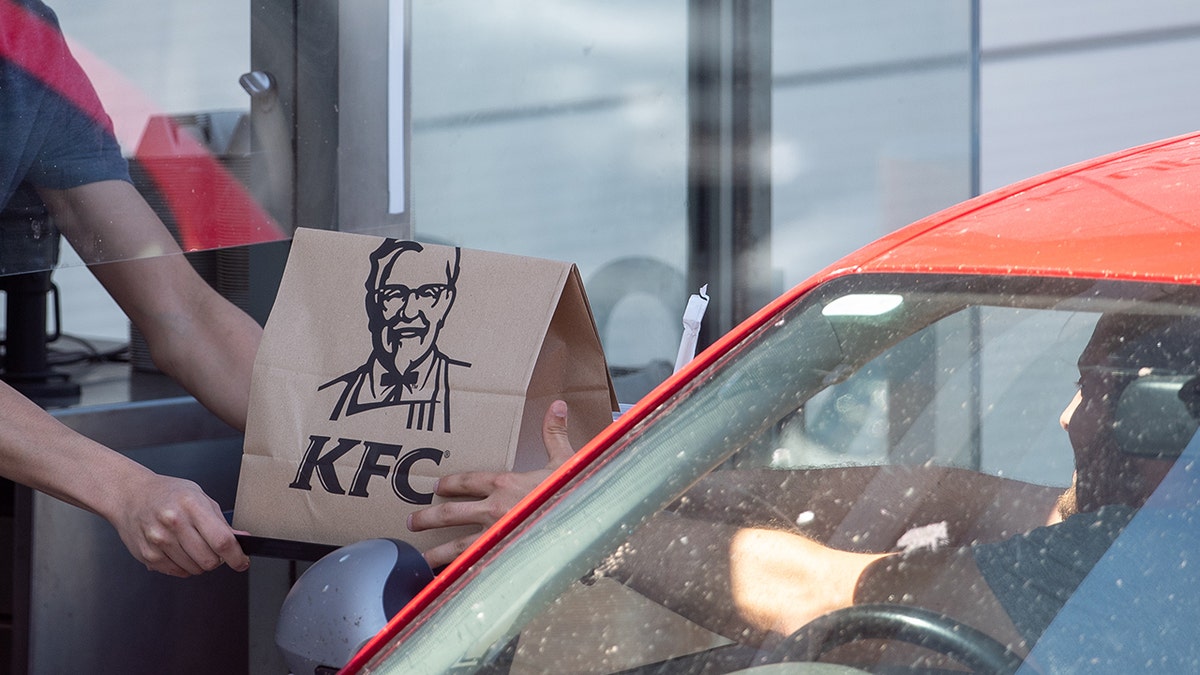 A member of staff hands an order to a customer at a KFC drive-thru in Leicester as the fast food chain reopened hundreds of its restaurants as drive-thru and pick-up locations after the introduction of measures to bring the country out of lockdown. More than 500 locations will be reopened with a limited menu by the end of the week.