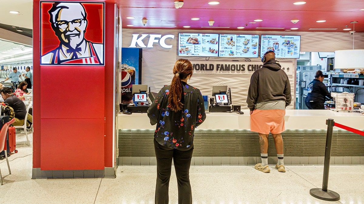 Customers seen from behind ordering KFC at Miami International Airport.