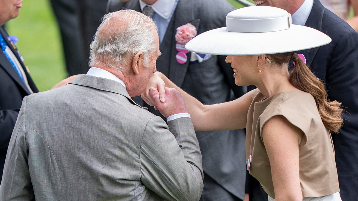 King Charles kissing Princess Eugenie's hand.