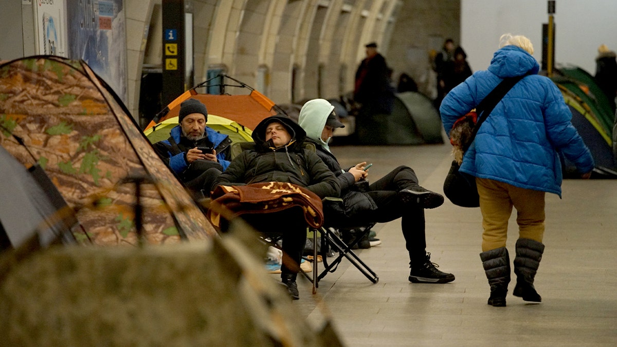 People sit and walk along a subway platform as they shelter underground during an air raid.