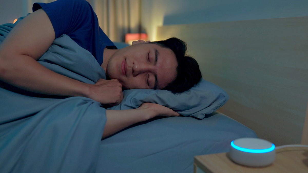 man sleeps with sound machine on nightstand