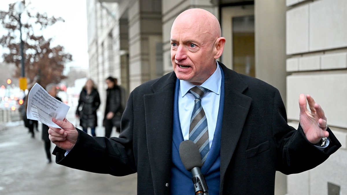 Mark Kelly answers questions from reporters near a courthouse entrance.