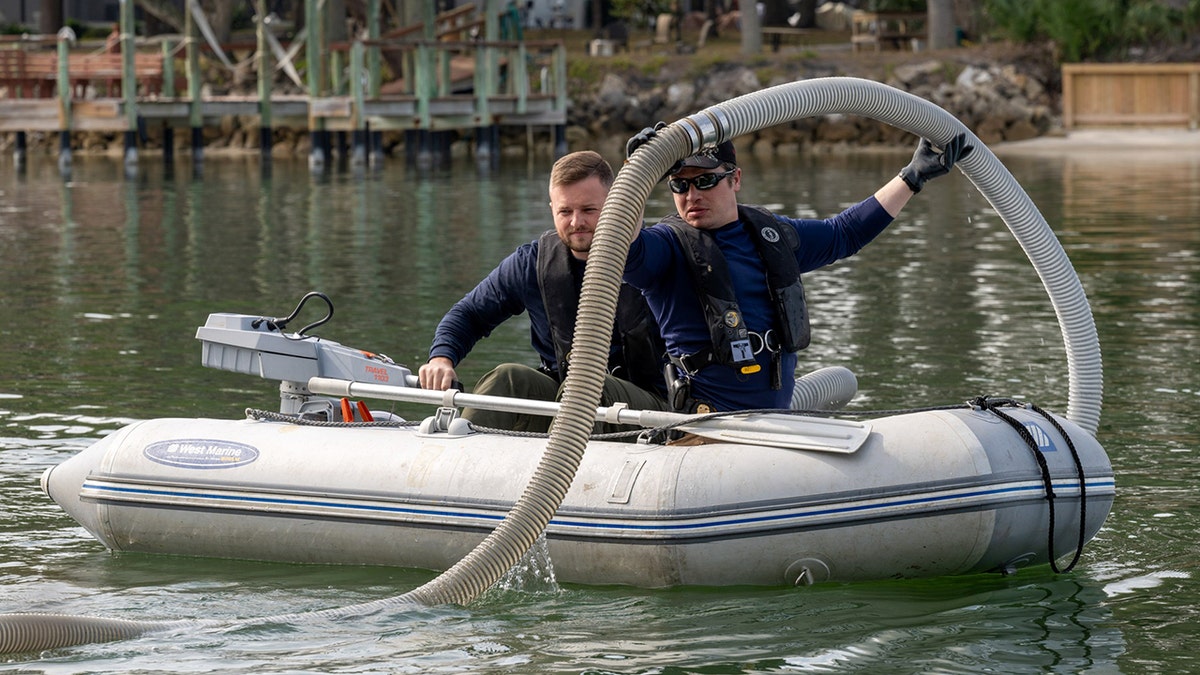 investigators searching waterway on a boat