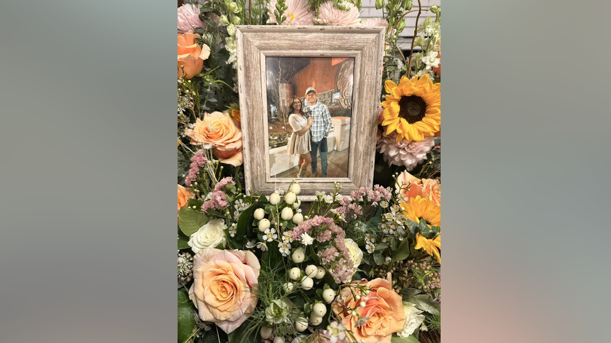A framed photo of Fletcher Harris and Skylar Provenza surrounded by flowers in a memorial display