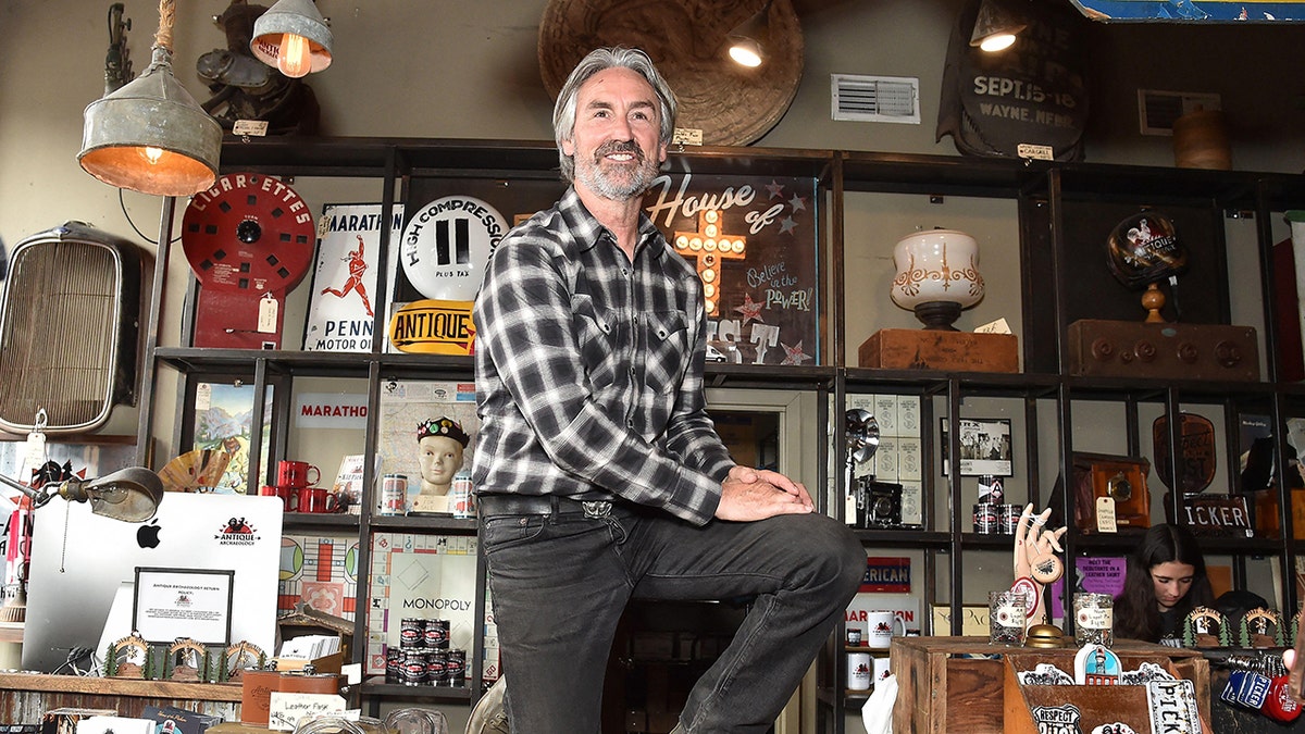 Mike Wolfe posing in front of his store smiling.