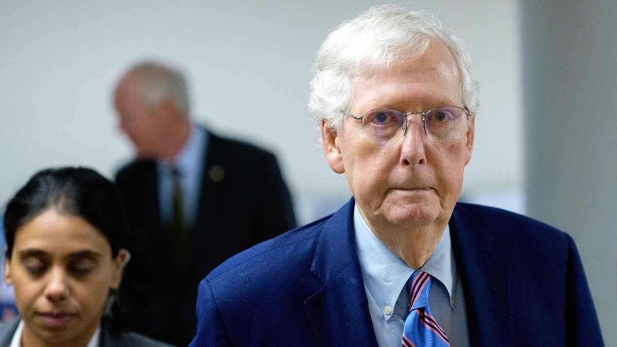 Mitch McConnell walking in front of his assistants