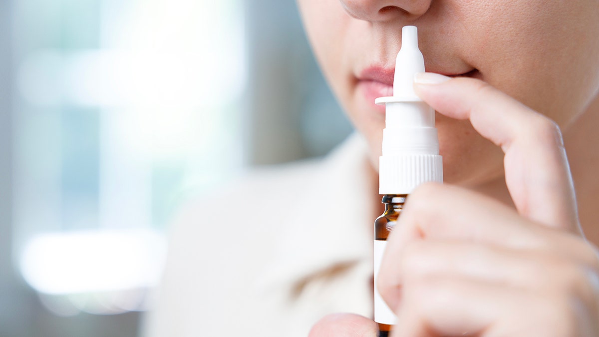 close-up of woman inserting nasal spray into nose