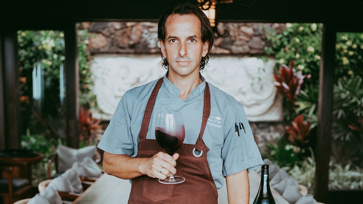 Nick Mastrascusa holds a glass of wine while posing for a photo