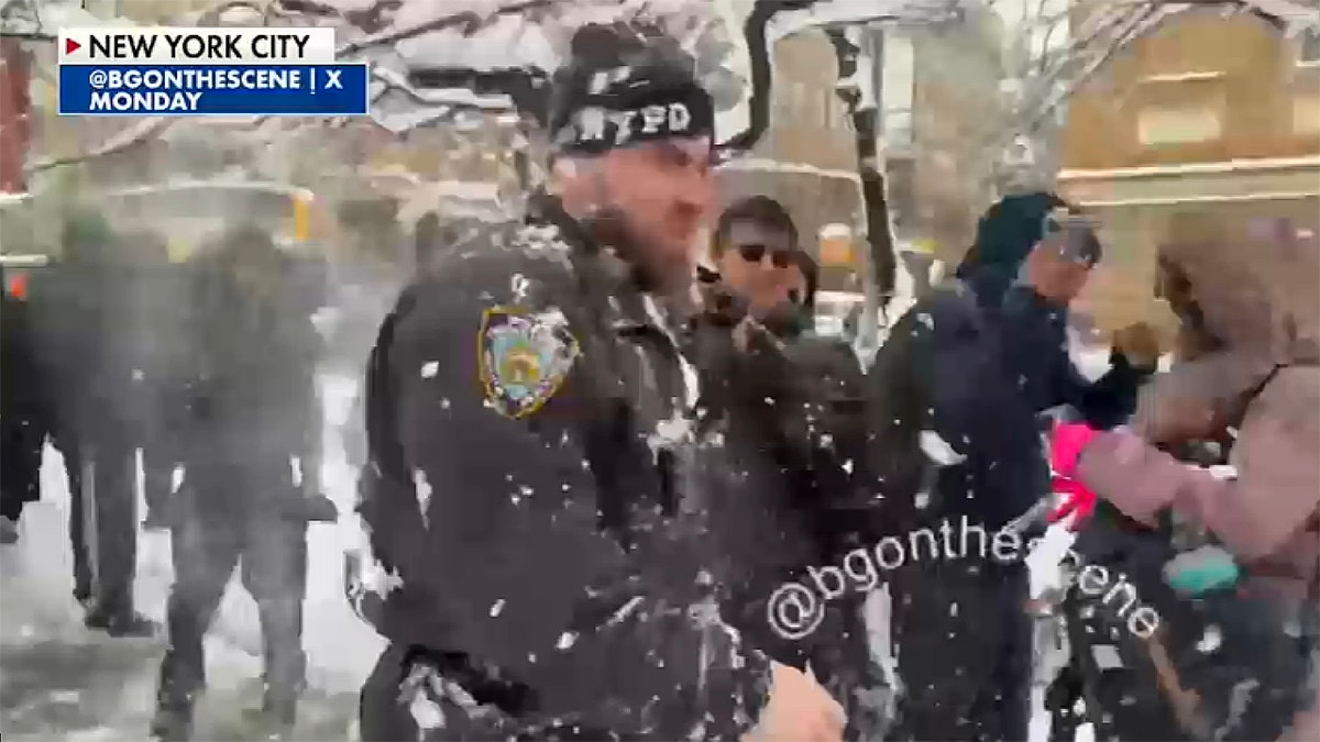 An NYPD officer is pelted with snow