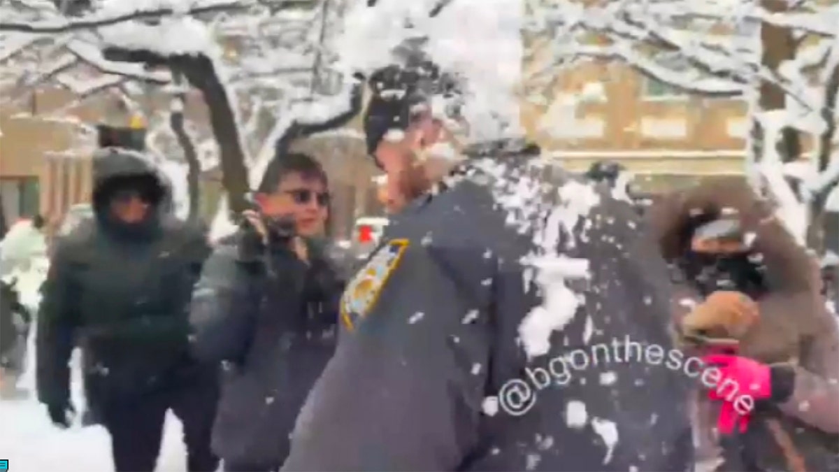 An NYPD officer is pelted with snow