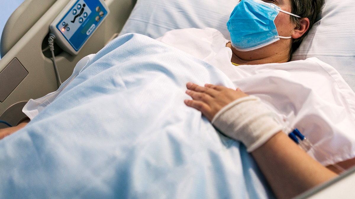 Paciente femenina con sobrepeso con mascarilla acostada en una cama de hospital moderna