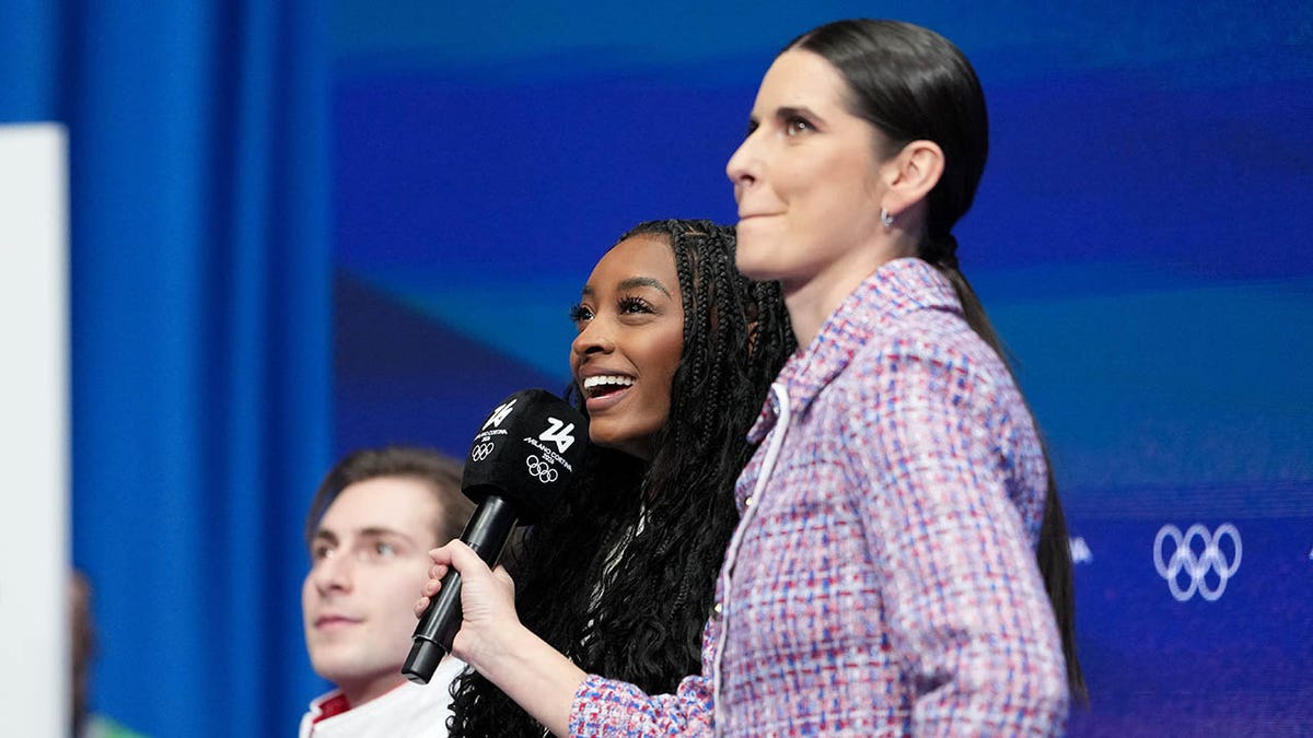 সিমোন বাইলস একজন ঘোষকের সাথে কথা বলছেন