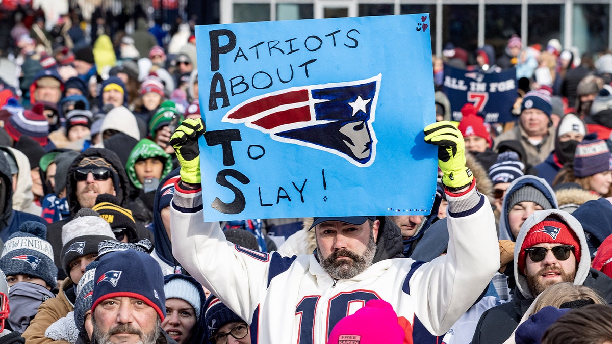 Patriot fans cheering and waving during a send off rally at Gillette Stadium.