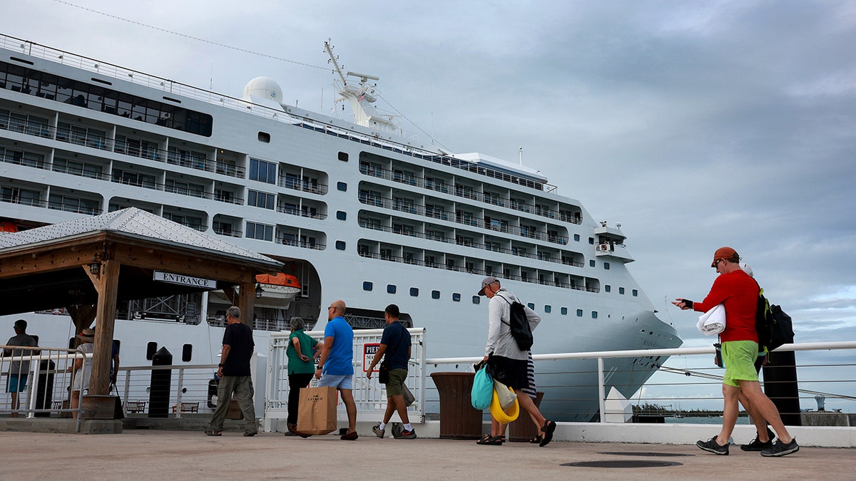 Passengers walking toward a luxury cruise ship during embarkation at port.