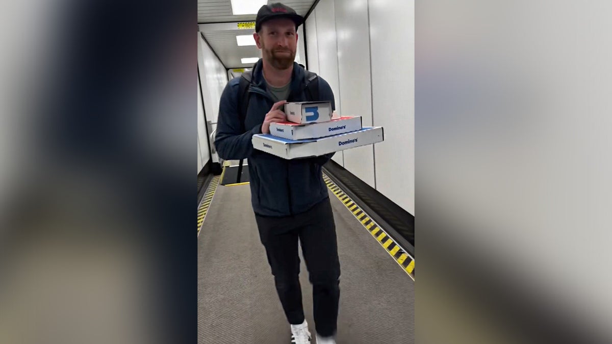 Ali Van De Graaff's husband boarding plane while holding boxes of pizza.