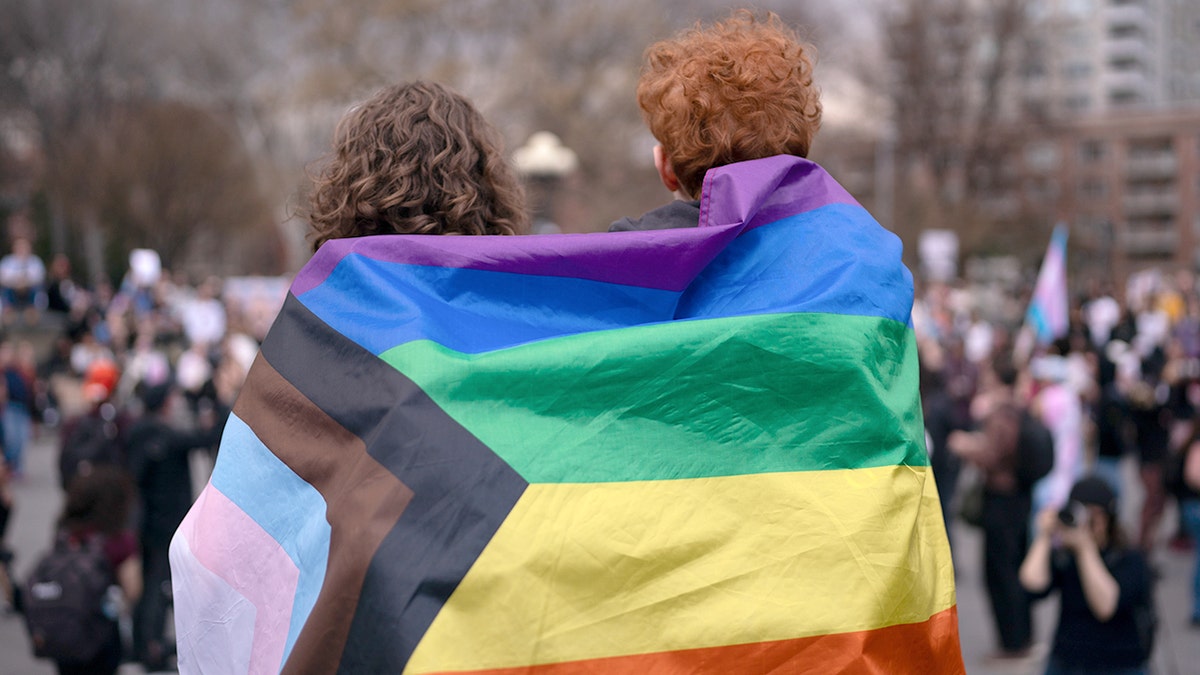 Two people wrapped in pride flag