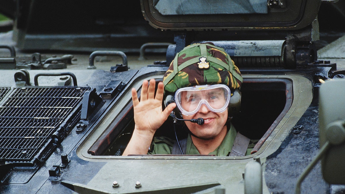 Prince Andrew popping his head out of a tank and smiling at the camera in 1989.