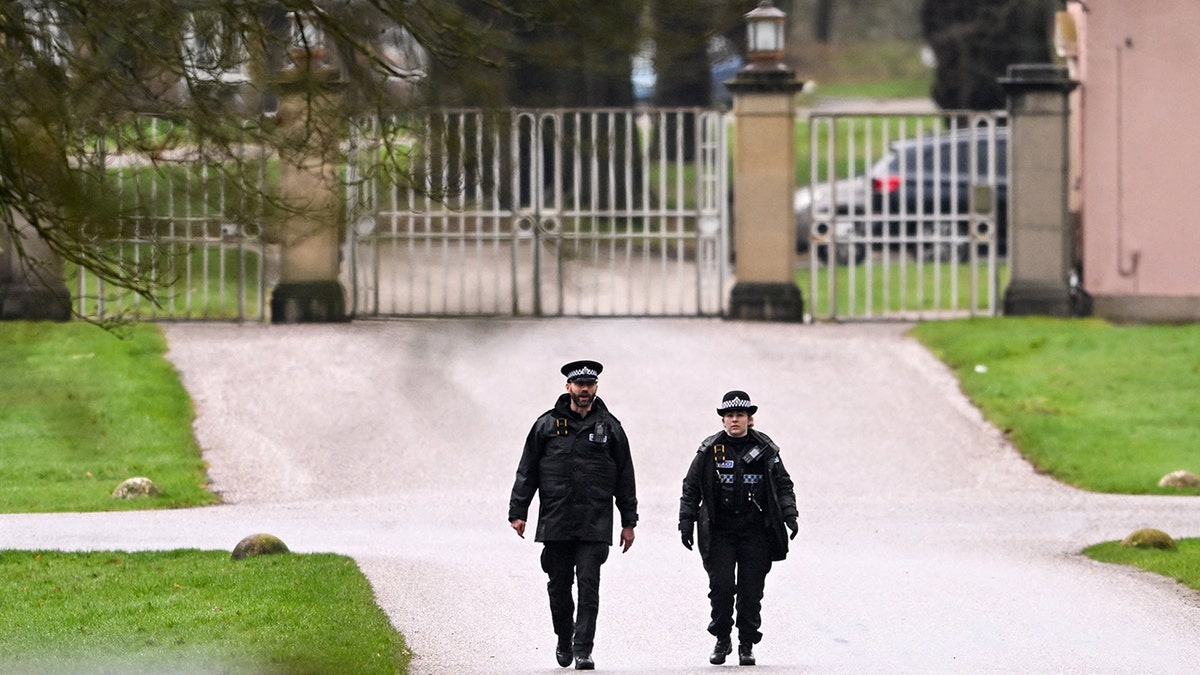 Police officers walking near the entrance to the former residence of Andrew Mountbatten Windsor.