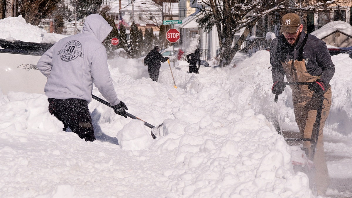 People shovel heavy snow from their driveways after a major winter storm blanketed the area.