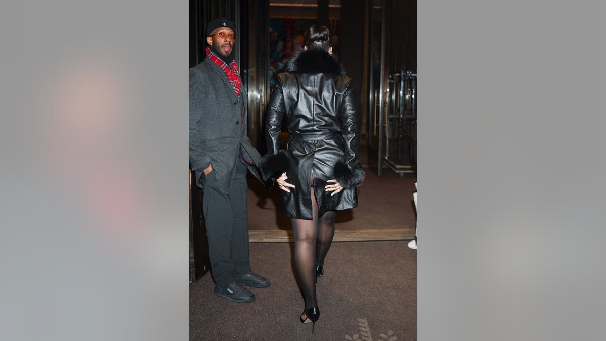 Rihanna pulling the slit of her jacket back together after her wardrobe malfunction