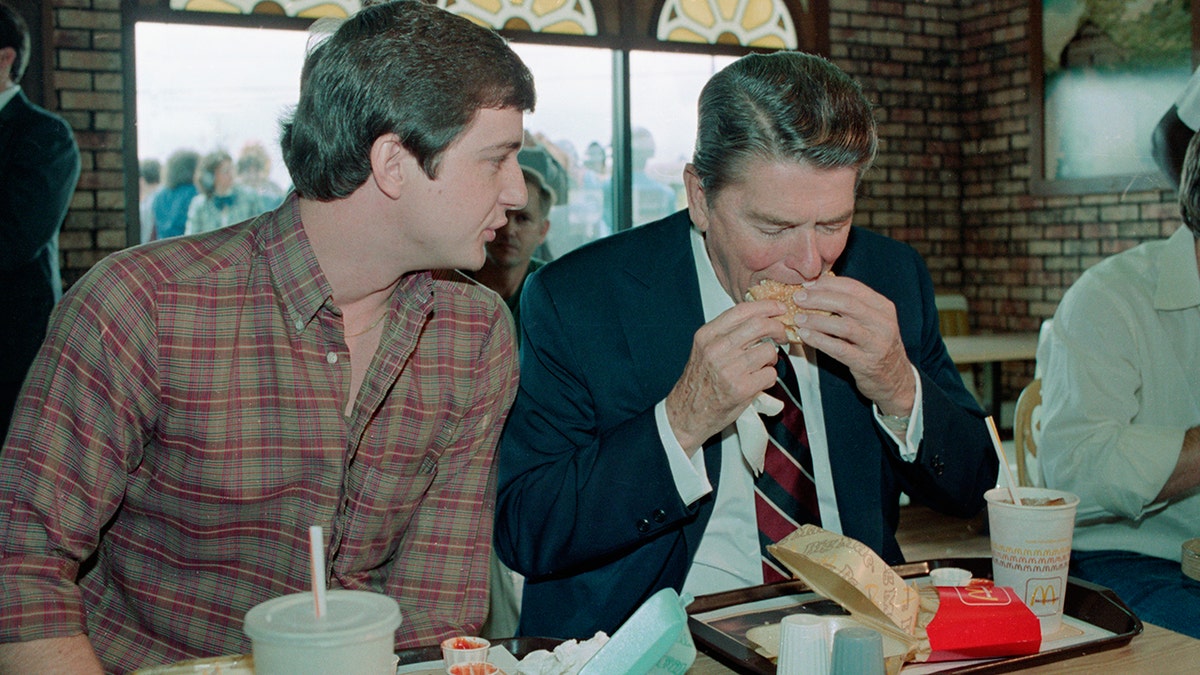 Ronald Reagan talking with a constituent while biting into a Big Mac on a campaign stop in 1984, seen sitting in McDonald's.