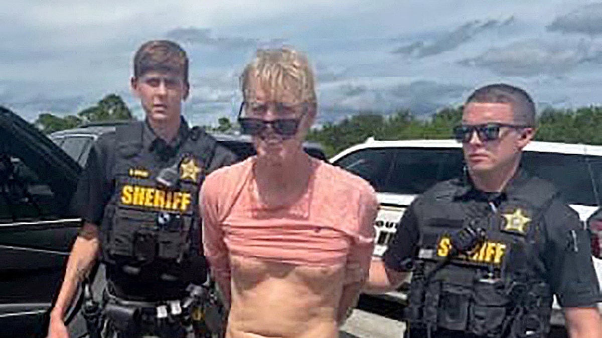 Ryan W. Routh stands handcuffed between two deputies after arrest near Palm City Florida
