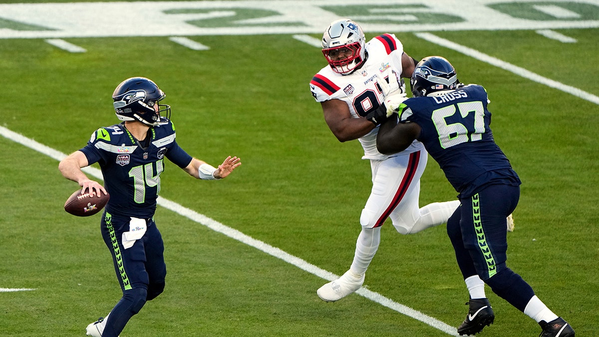 Seattle Seahawks quarterback Sam Darnold (14) drops back to pass as offensive tackle Charles Cross (67) defends against a rush by New England Patriots defensive end Milton Williams (97) during the first half of the NFL Super Bowl 60 football game, Sunday, Feb. 8, 2026, in Santa Clara, Calif. (AP Photo/Charlie Riedel)