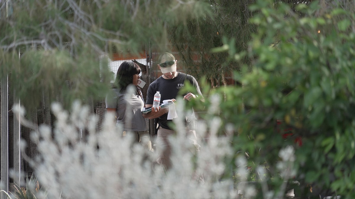 Investigators walking past houses and through a neighborhood in search of Nancy Guthrie.