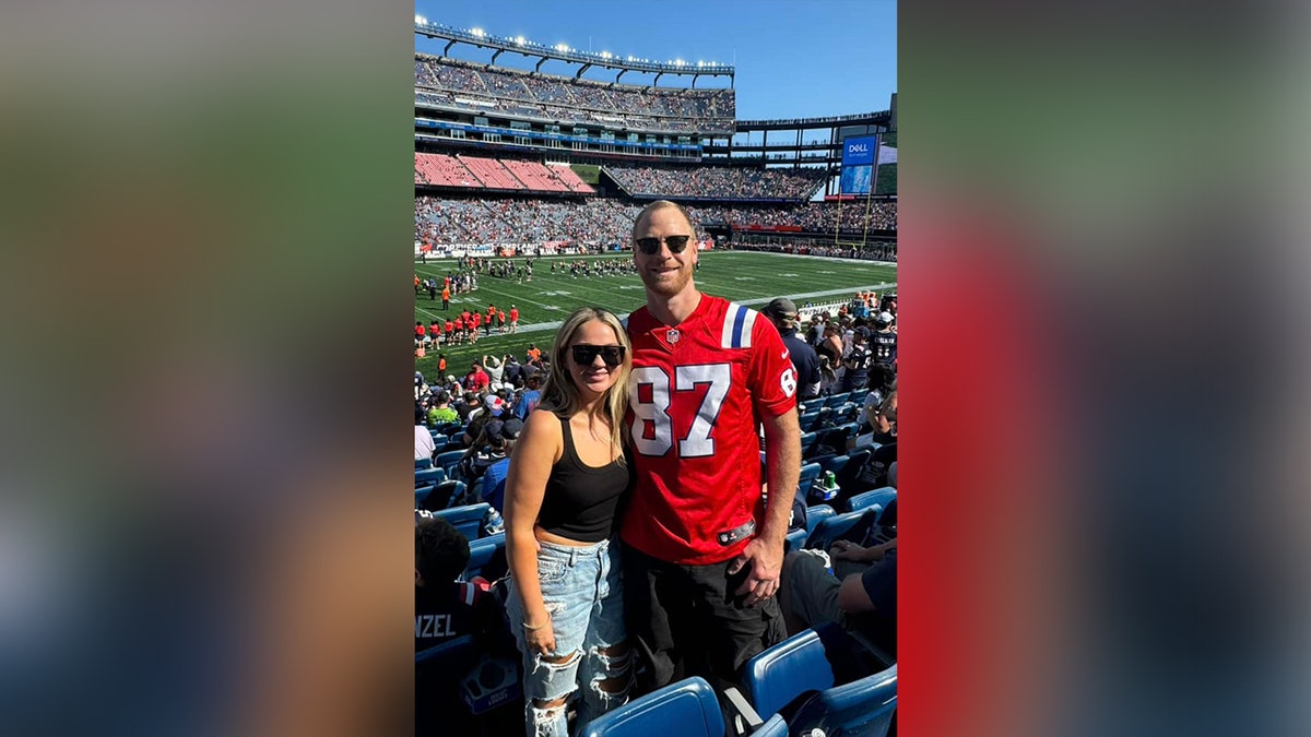 A man and woman standing in the stands of a football stadium.